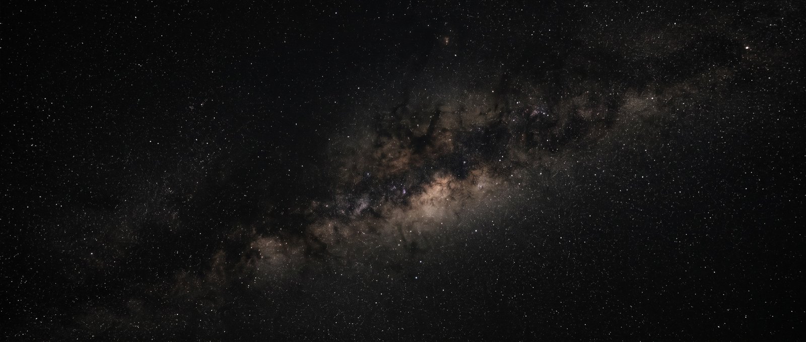 Deep space, a faint band of interstellar dust across a dense star field